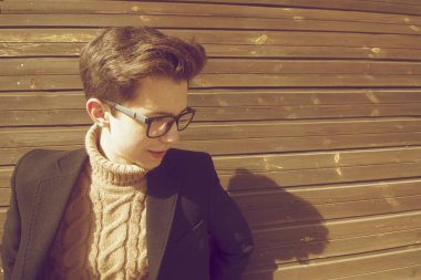 Ayakta, eski şehir bina ahşap duvara yakın duran bir gülümseme pozlar genç adamla. Bir siyah ışık Mont, siyah çerçeveli gözlük giyinmiş.