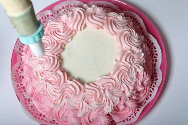 Una mujer sostiene una bolsa de pastelería con crema. Decora con su pastel . — Foto de Stock