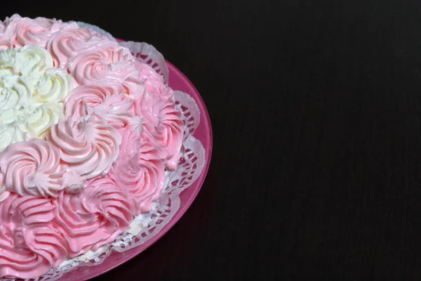 Biscuit cake, decorated with a cream with shades of pink. On a dark background. — Stock Photo, Image