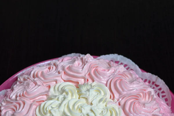 Ciasto biszkoptowe, ozdobione krem z odcieniami różu. Na ciemnym tle. — Zdjęcie stockowe
