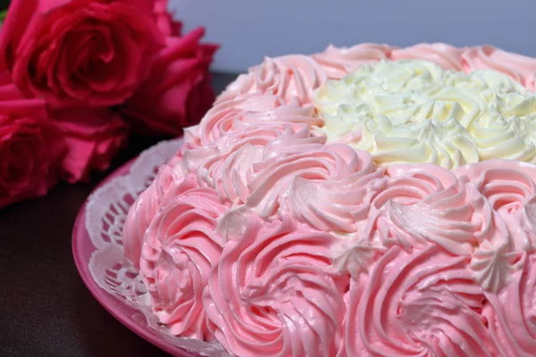 Pastel de galletas, decorado con una crema con tonos de rosa. Cerca hay un ramo de rosas . — Foto de Stock