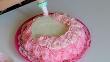 Bir kadın bir yanal bisküvi pasta pembe krema ile süsle. Hamur işi çanta yardımı ile.