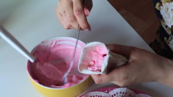女性はペストリー袋にピンクのクリームを置きます 白いクリームで広がって次のスポンジ ケーキ — ストック動画