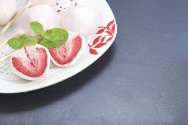 Yoğurt çilek. Çilek ahşap şiş üzerinde giyinmiş ve yoğurt daldırılır. Yakınlarda tatlı iki yarısı vardır. Görünür kırmızı sulu çilek eti. Nane yaprakları ile dekore edilmiş.