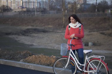 Kız Park edilmiş bir bisikletin üzerine eğilir. Bahar döngüsünde istirahat.