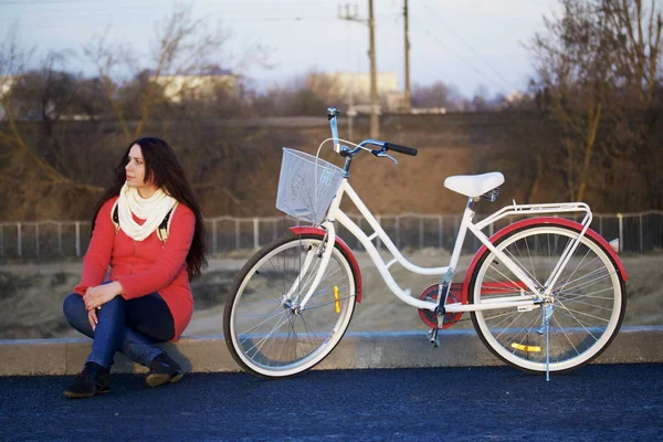 Das Mädchen sitzt neben einem geparkten Fahrrad. Ruhe auf den Frühjahrszyklus. — Stockfoto
