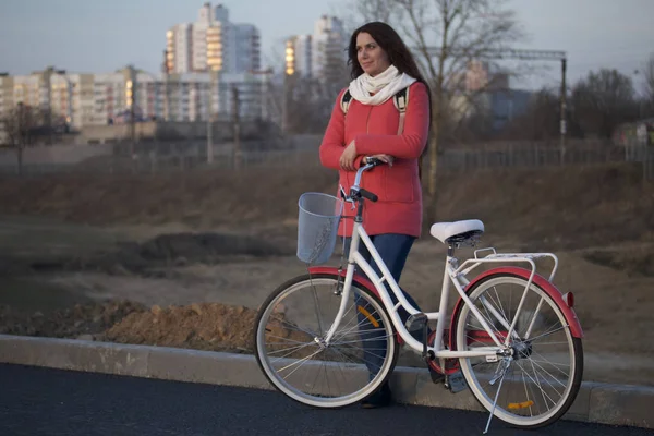 Kız Park edilmiş bir bisikletin üzerine eğilir. Bahar döngüsünde istirahat.