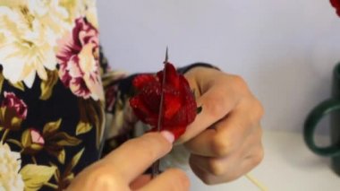 Bir kadın çilekten gül yapar. Çilek bir sopa üzerinde giyinmiş, kadın bir bıçak ile yaprakları keser. Yakınlarda hazır çiçekler vardır.