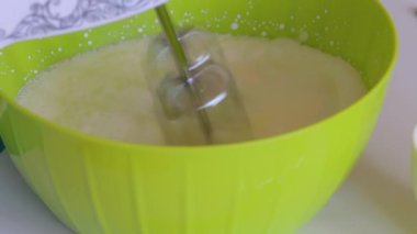 Bir kadın Blender ile krem kamçıla. Tatlı yapmak için diğer malzemelerin yanında. Şeker ve çilek..
