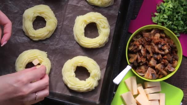 一个女人把奶酪环放在烤盘上的土豆泥灌满 旁边的其他食材烹饪晚餐 — 图库视频影像
