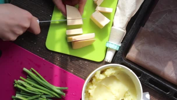 妇女在切菜板上切奶酪 旁边的其他食材烹饪晚餐 土豆泥 新鲜洋葱羽毛 — 图库视频影像