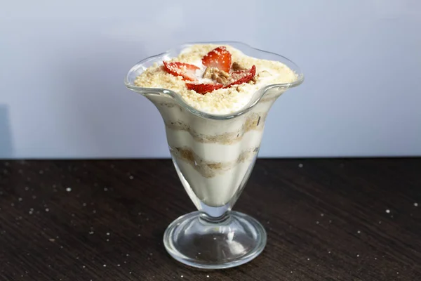 Postre en una copa de vidrio. Capas colocadas migas de galletas y crema. Decorado con rodajas de fresa. Con la adición de nuez . —  Fotos de Stock