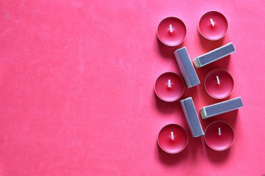 Bir satırda düzenlenmiş Dekoratif mumlar ve kibrit kutuları. Pembe bir arka planda.