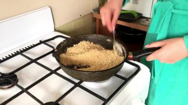 Bir kadın kızartma tavasında bisküvi kırıntıları kızartır. Tatlı hazırlanması için.