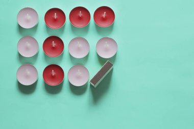 Bir satırda düzenlenmiş Dekoratif mumlar ve kibrit kutuları. Nane arka planda.