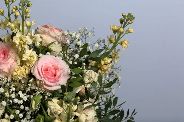 A large bouquet of different flowers. Several types of roses and other plants to decorate the bouquet.