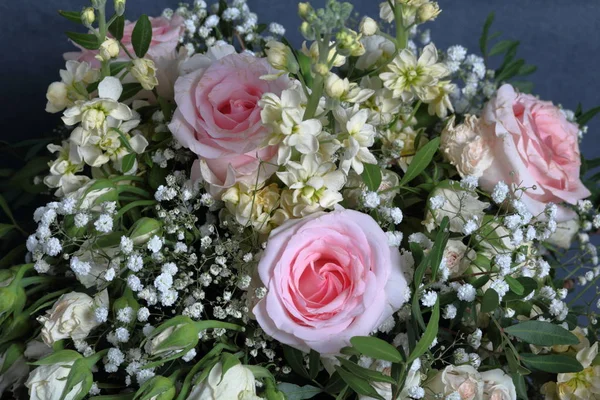 A large bouquet of different flowers. Several types of roses and other plants to decorate the bouquet.