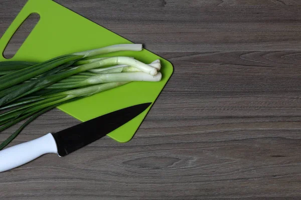 Verduras frescas cuidadosamente colocadas en la mesa. Cebollas aromáticas. Junto al cuchillo de cocina y la tabla de cortar. Ingredientes para ensalada saludable . — Foto de Stock