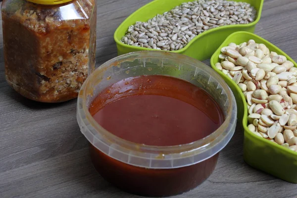 Mel em um recipiente. Próximo a recipientes separados de amendoim e sementes de girassol. Ingredientes para fazer halva . — Fotografia de Stock