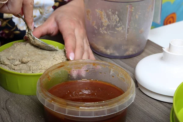 한 여성이 꿀, 땅콩, 해바라기 씨로 만든 할바 요리한 숟가락으로 물개합니다. 용기에 다음 꿀. 할바 만들기를 위한 재료 및 도구. — 스톡 사진