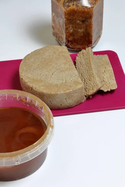 Gesneden Halva van honing, pinda's en zonnebloempitten. In de buurt van honing in verschillende containers. Ingrediënten en hulpmiddelen voor het maken van Halva. — Stockfoto