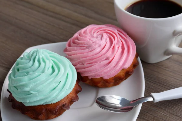 Deux gâteaux à la crème et une tasse de café. Les gâteaux reposent sur une soucoupe. Près d'une cuillère à café . — Photo