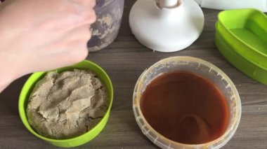 Bir kadın kabına bal, doğranmış yer fıstığı ve tohum karışımı ekler. Helva şekillendirme kiçin.