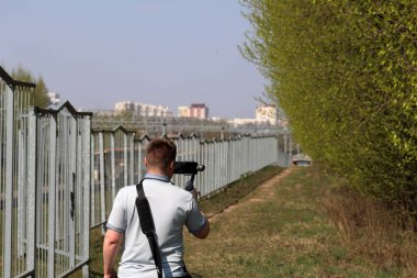 Akıllı telefondan videoya kaydolan genç bir adam. Düzgün çekim ler elde etmek için gimbal kullanır. Film çekimini yakından izlemek.