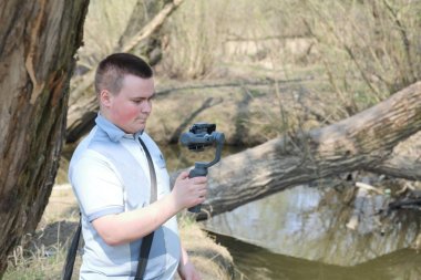 Akıllı telefondan videoya kaydolan genç bir adam. Düzgün çekim ler elde etmek için gimbal kullanır. Film çekimini yakından izlemek.