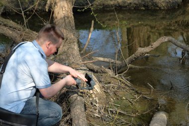 Akıllı telefondan videoya kaydolan genç bir adam. Düzgün çekim ler elde etmek için gimbal kullanır. Ekrana dokunarak kaydı kontrol eder.