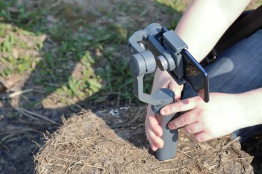 Akıllı telefondan videoya kaydolan genç bir adam. Düzgün çekim ler elde etmek için gimbal kullanır. Film çekimini yakından izlemek.