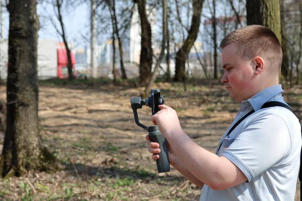 Ein junger Mann filmt mit seinem Smartphone. verwendet Gimbal, um glatte Aufnahmen zu erhalten. Steuerung der Aufnahme durch Berührung des Bildschirms. — Stockfoto