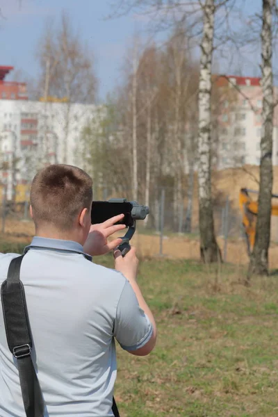 Ein junger Mann filmt mit seinem Smartphone. verwendet Gimbal, um glatte Aufnahmen zu erhalten. Steuerung der Aufnahme durch Berührung des Bildschirms. — Stockfoto