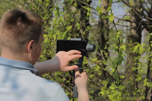 Un jeune homme filmant sur un smartphone. Utilise la carabine pour obtenir des tirs lisses. Contrôle l'enregistrement en touchant l'écran . — Photo
