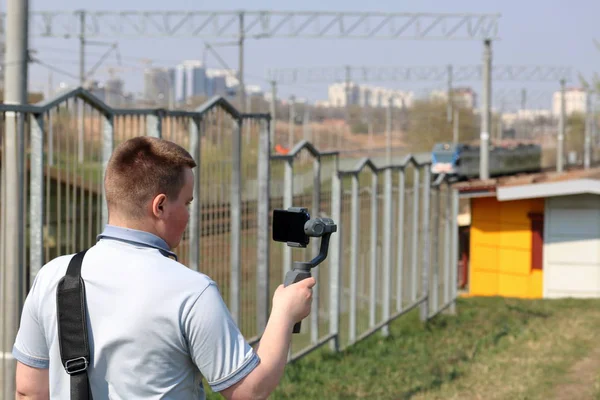 スマートフォンでビデオ撮影した若い男。ジンバルを使用して滑らかなフッテージを取得します。映画撮影をじっくり見る. — ストック写真