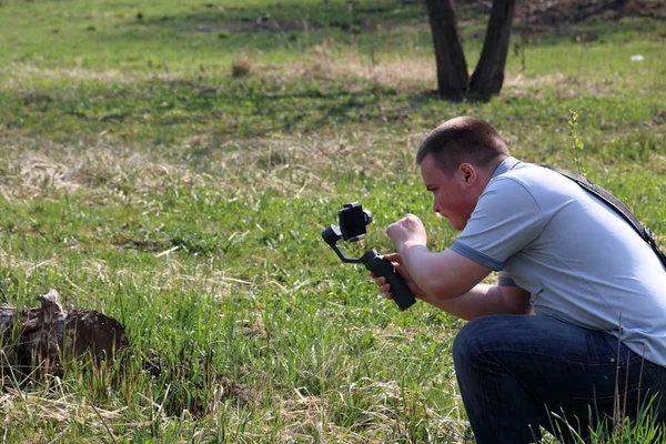 Akıllı telefondan videoya kaydolan genç bir adam. Düzgün çekim ler elde etmek için gimbal kullanır. Ekrana dokunarak kaydı kontrol eder. — Stok fotoğraf