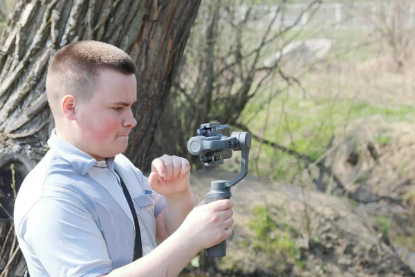 Ein junger Mann filmt mit seinem Smartphone. verwendet Gimbal, um reibungsloses Filmmaterial zu erhalten. Aufmerksam beim Filmdreh. — Stockfoto