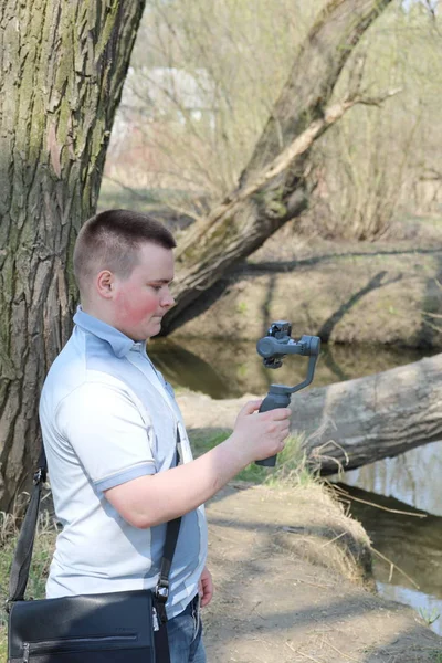 Ein junger Mann filmt mit seinem Smartphone. verwendet Gimbal, um reibungsloses Filmmaterial zu erhalten. Aufmerksam beim Filmdreh. — Stockfoto