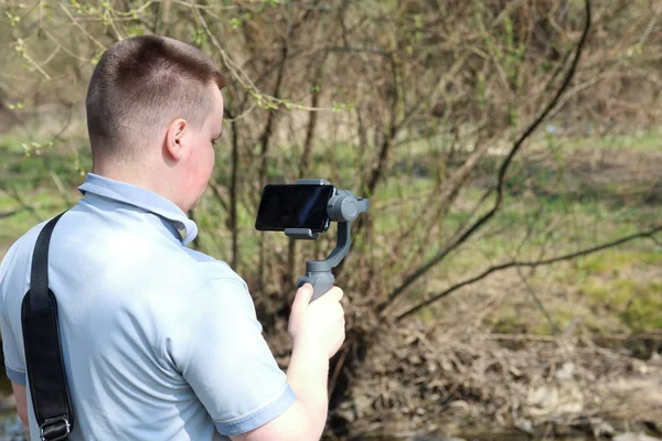 Un jeune homme filmant sur un smartphone. Utilise la carabine pour obtenir des images lisses. Regardez de près le tournage du film . — Photo