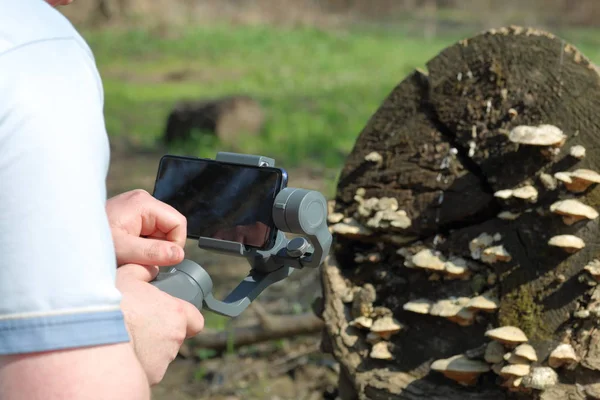 Ein junger Mann filmt mit seinem Smartphone. verwendet Gimbal, um reibungsloses Filmmaterial zu erhalten. Aufmerksam beim Filmdreh. — Stockfoto