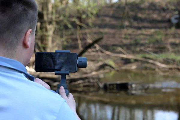 Un jeune homme filmant sur un smartphone. Utilise la carabine pour obtenir des images lisses. Regardez de près le tournage du film . — Photo