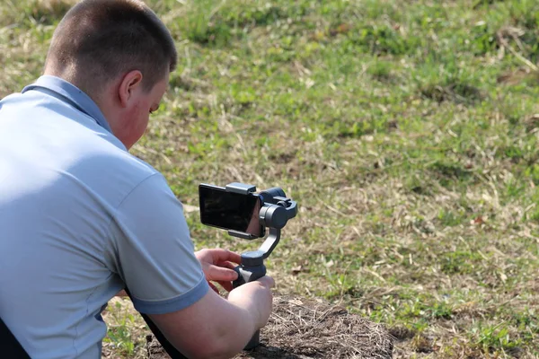 Un joven grabando en un smartphone. Utiliza gimbal para obtener imágenes suaves. Ver de cerca el rodaje de la película . — Foto de Stock