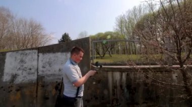 Genç bir adam spring parkta bir akıllı telefon video çekiyor. Elektronik gimbal kullanarak pürüzsüz çerçeveler için.
