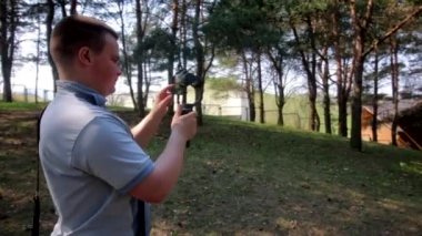 Genç bir adam spring parkta bir akıllı telefon video çekiyor. Elektronik gimbal kullanır.