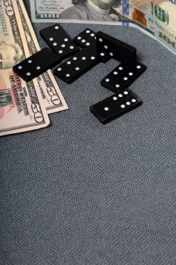 Kaba gri bir bezle kaplı bir yüzeyde domino eklemleri. Yakında farklı mezheplerden birkaç dolarlık banknotlar var..