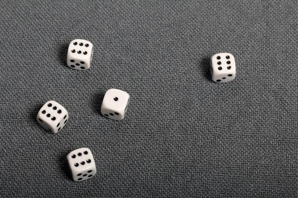 Білі кубики з чорними позначками. Вони лежать на поверхні, покритій грубою сірою тканиною. Вид зверху . — стокове фото