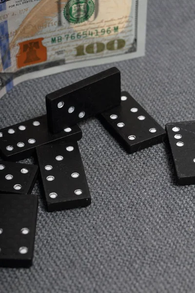 Domino knokkels op een oppervlak bedekt met een grove grijze doek. In de buurt is een honderd dollar Bill. — Stockfoto