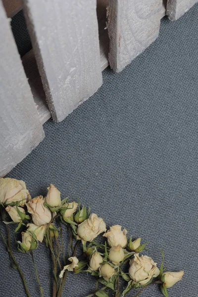 Rose beige essiccate. Sullo sfondo di tessuto grigio struttura ruvida. Nelle vicinanze si trova una scatola di legno, dipinta di bianco . — Foto Stock