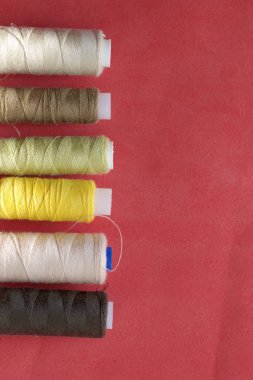 Farklı renklerde makaralar pembe bir arka plan üzerinde üst üste düzenlenmiştir. Düz yatıyordu tarzında.