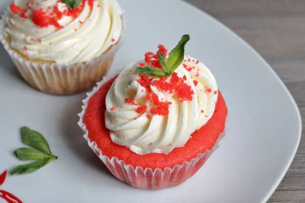 Rode fluwelen cupcake. De afgewerkte taarten zijn op de plaat. Versierd met muntblaadjes. — Stockfoto